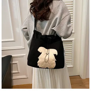 Detail of black corduroy tote bag with white plush dog patch and drawstring closure