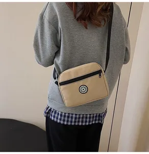 Khaki nylon crossbody bag shown from side back view on model with sport badge detail