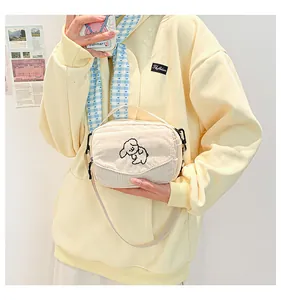 Detail van de crème corduroy mini-tas met schattig hondenborduurwerk en schouderband