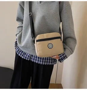 Close-up of khaki nylon crossbody bag showing the SPORT logo patch and black zipper detail