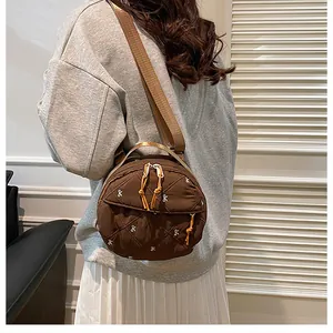 Detailed side view of round quilted crossbody bag with embroidery and wide strap