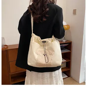 Detail of off-white corduroy tote bag with plush animal embroidery and drawstring closure