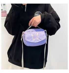 Détail d'un petit sac bandoulière en velours côtelé violet avec broderie lapin
