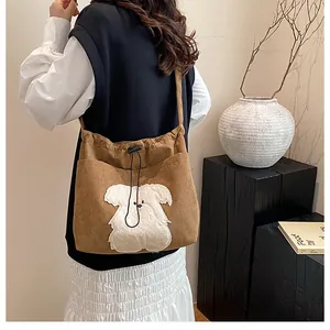 Detail of a brown corduroy tote bag with a white plush puppy patch and drawstring closure