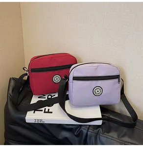 Detail of red and purple nylon crossbody bags with round sport logos and adjustable straps