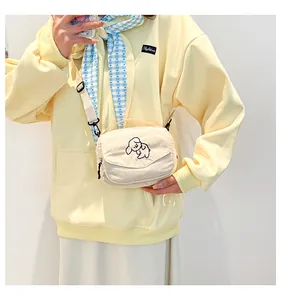 Detail van de gebroken witte corduroy crossbody tas met schattig geborduurd hondje