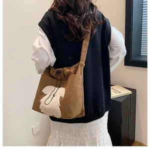 Brown corduroy crossbody tote with cute white plush puppy patch shown on a model