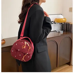 Detail of wine red quilted crossbody bag with butterfly embroidery and soft fabric strap