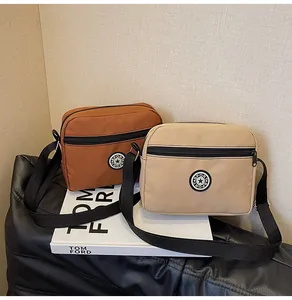 Detail of caramel and beige nylon crossbody bags with sport logo on white books