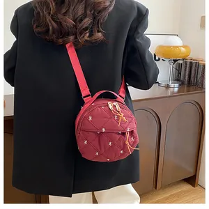 Fashionable red quilted round bag with bow embroidery shown on a model in a cozy interior