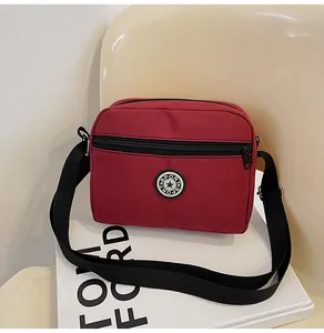 Detail of dark red nylon crossbody bag with black SPORT logo on a white magazine