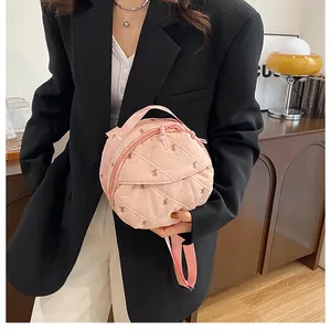 Detail of pink quilted round bag with bow embroidery and premium zipper closure