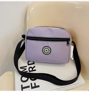 Detail of purple nylon crossbody bag with sport logo on a casual cream background