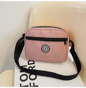 Detailed macro view of pink nylon crossbody bag with black SPORT logo and adjustable strap