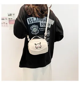 Gros plan du petit sac bandoulière en velours côtelé crème porté par un mannequin