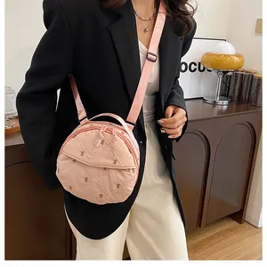 Detailed close-up of pink round quilted crossbody bag with embroidered bow details