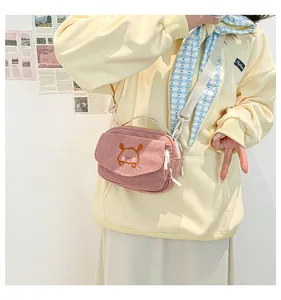 Détail d'un petit sac bandoulière en velours côtelé rose avec broderie mignonne sur mannequin