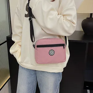 Pink waterproof nylon crossbody bag with adjustable strap and front zipper pocket
