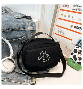 Detail van een zwarte corduroy crossbodytas met een schattig geborduurd wit hondje
