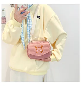 Détail du sac bandoulière rose en velours côtelé avec broderie et sangle blanche