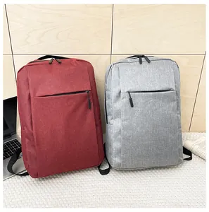 Business laptop backpacks in burgundy and grey shown on floor with study accessories