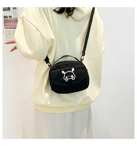 Détail du petit sac bandoulière en velours côtelé noir avec broderie sur le mannequin