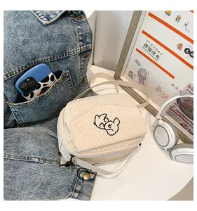 Detail van de crème corduroy vierkante tas met schattig geborduurde beer en riem