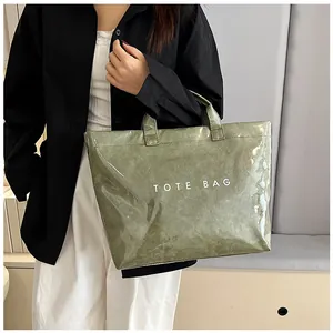 Dettaglio di una borsa tote verde oliva con trama vintage e stampa bianca TOTE BAG sul lato