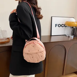 Pink quilted round crossbody bag with bow embroidery and top handle in a lifestyle setting