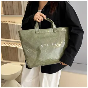 Dettaglio della borsa tote impermeabile in PVC verde scuro con testo TOTE BAG bianco