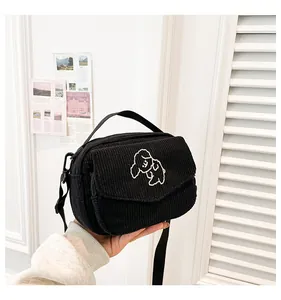 Detail van zwarte corduroy mini-tas met puppyborduurwerk en verstelbare schouderriem
