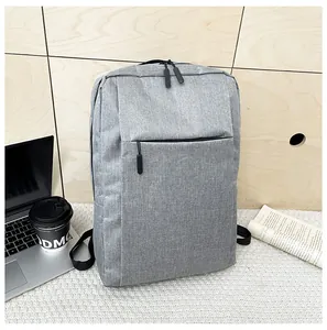 Gray business backpack with hidden front pocket shown on desk with lifestyle accessories