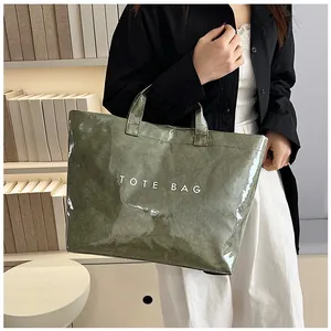 Dettaglio della borsa tote verde scuro con texture stropicciata e stampa TOTE BAG bianca