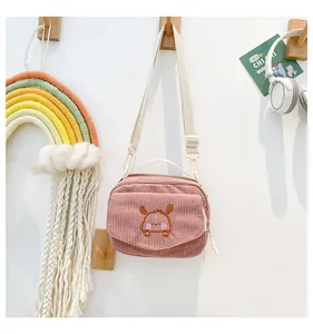 Vue détaillée du petit sac bandoulière en velours côtelé rose avec broderie et porte-clés
