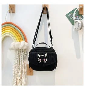 Détail du sac bandoulière en velours côtelé noir avec broderie lapin blanc et bandoulière