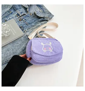 Détail du sac bandoulière en velours côtelé lavande avec broderie et sangle blanche
