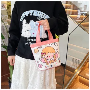 Detail der Canvas-Minitasche mit Cartoon-Mädchen-Print und rosa Besatz in der Hand