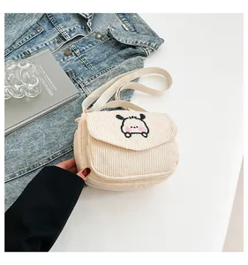 Détail de la texture velours côtelé et broderie chiot mignon sur un mini sac beige doux
