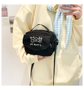 Detail van de zwarte corduroy schoudertas met schattig konijnenborduurwerk en tekst