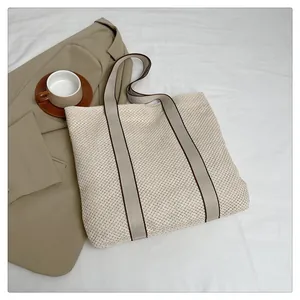 Detailaufnahme der gewebten Stroh-Tote-Bag mit feiner Textur und Kontrast-Schultergurten