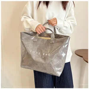 Dettaglio della borsa tote grigia lucida in PVC con chiusura magnetica e stampa