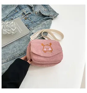 Détail d'un sac bandoulière en velours côtelé rose avec broderie animale et sangle en tissu