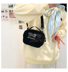 Detail van de schattige zwarte corduroy mini crossbodytas met witte cartoonborduurwerk