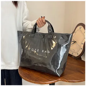 Dettaglio di una grande borsa tote grigio metallizzato con scritta TOTE BAG bianca