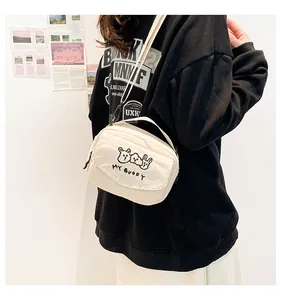 Detail van een crème corduroy crossbodytas met borduursel gedragen door een model