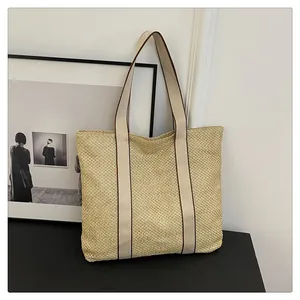Detail der Strohtasche mit Tragegriffen aus cremefarbenem Segeltuch und brauner Paspel