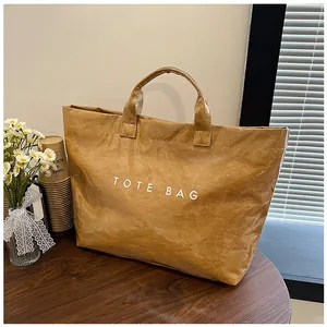 Dettaglio della borsa tote in carta Tyvek marrone con stampa TOTE BAG su tavolo in legno