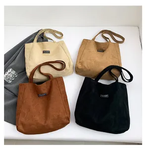 Quatre cabas en suédine beige, camel, marron et noir disposés à plat avec étiquette