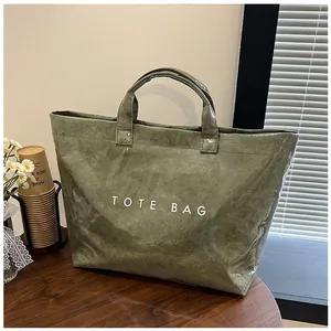 Dettaglio della borsa tote verde scuro con trama carta e scritta TOTE BAG stampata