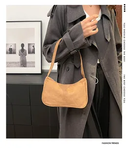 Detailopname van een lichtbruine suède hobo-tas gedragen door een model in stedelijke stijl